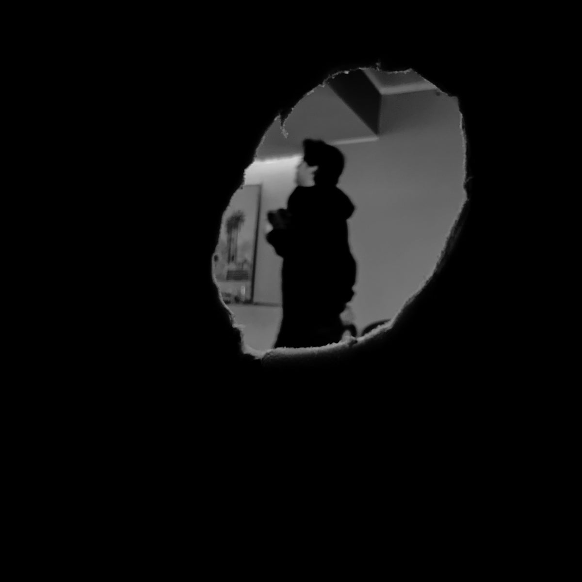 Silhouette of a person seen through a dark opening.