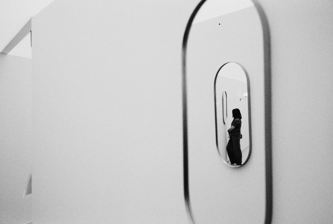 Woman reflected in an oval mirror on a white wall