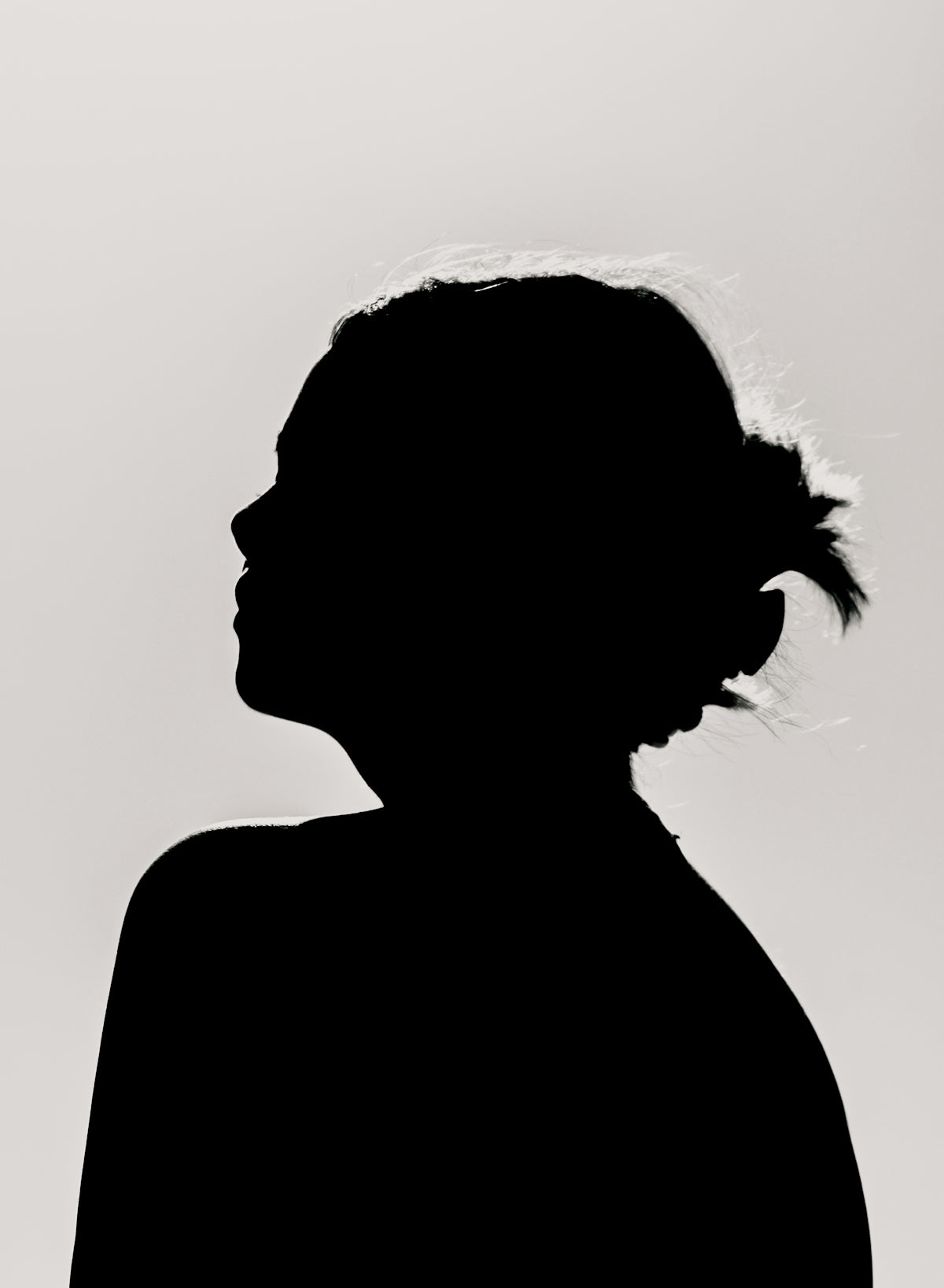 A silhouette of a person in profile with hair in a bun