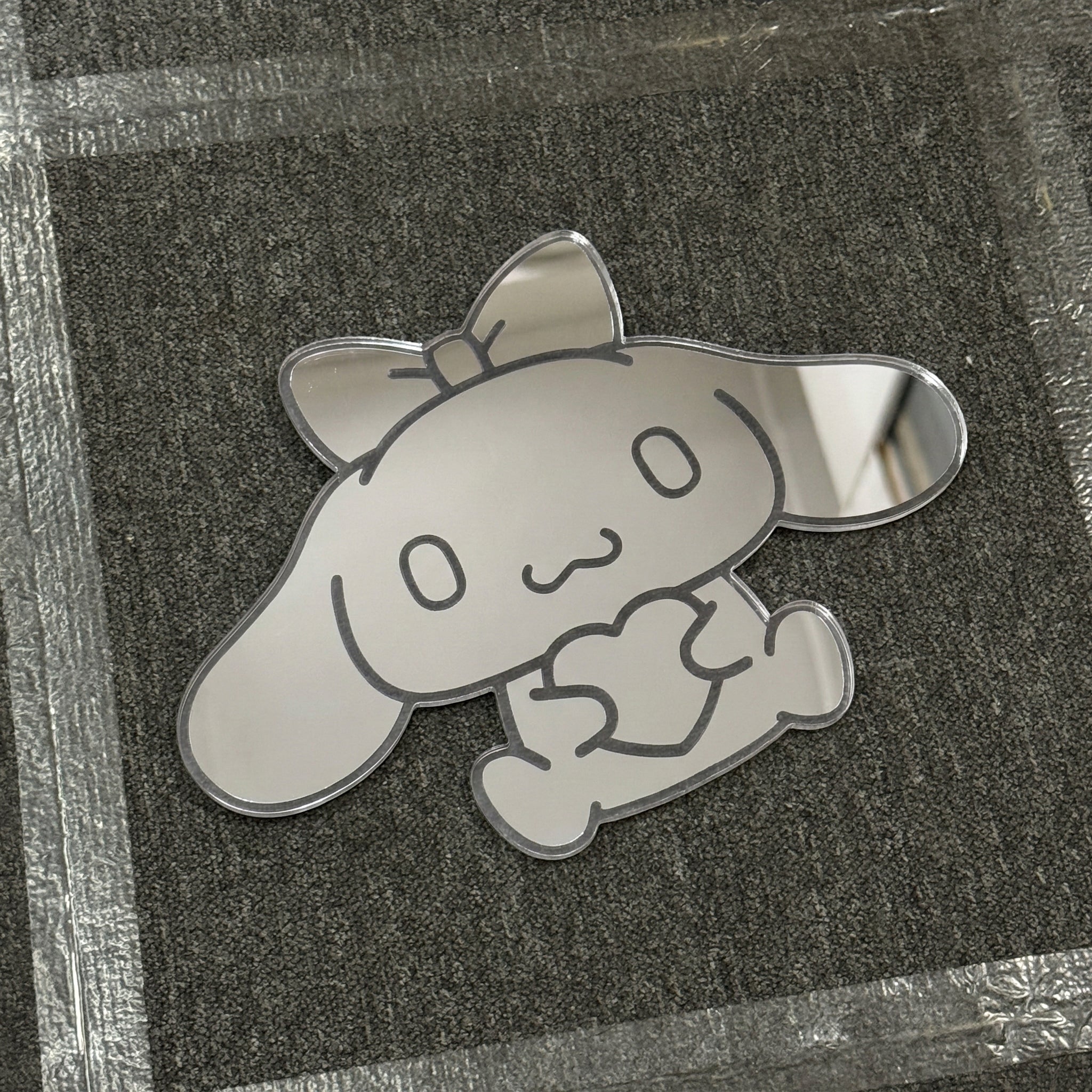 Bunny-shaped acrylic mirror displayed outdoors with potted plants